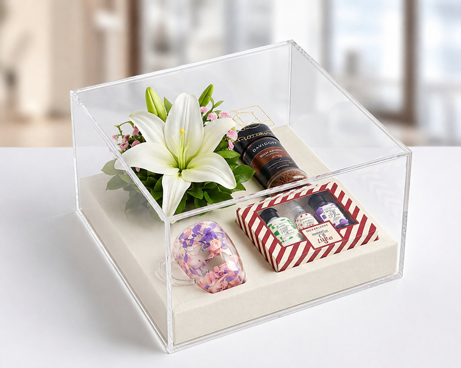 Corporate gift hamper in a clear acrylic box with flowers, coffee and gift set